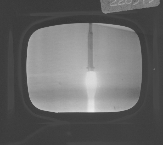 Schwarzes und weißes Foto eines Fernseherbildschirms, der eine Raketenstarts zeigt, mit Text oben drauf.