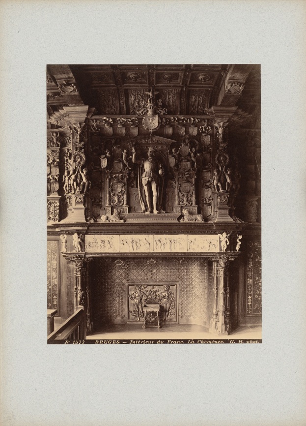 Ein altes Schwarz-Weiß-Foto eines Kamins mit einer zentralen Statue, umgeben von Skulpturen an den Wänden und der Decke, mit Text unten.
