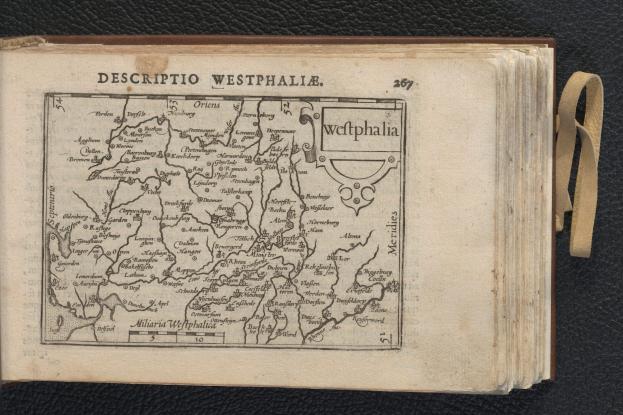 Ein aufgeschlagenes Buch mit einer detaillierten Karte von Westfalen darauf, das auf einer schwarzen Oberfläche liegt.