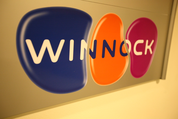 Leuchtend buntes "Winnock"-Schild an einer Wand angebracht, das eine Börse anzeigt.