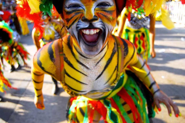Eine Gruppe von Menschen in bunten Kostümen und Schminke, mit einer Frau in einem Tigerkostüm, auf einem Karneval mit einem unscharfen Hintergrund.