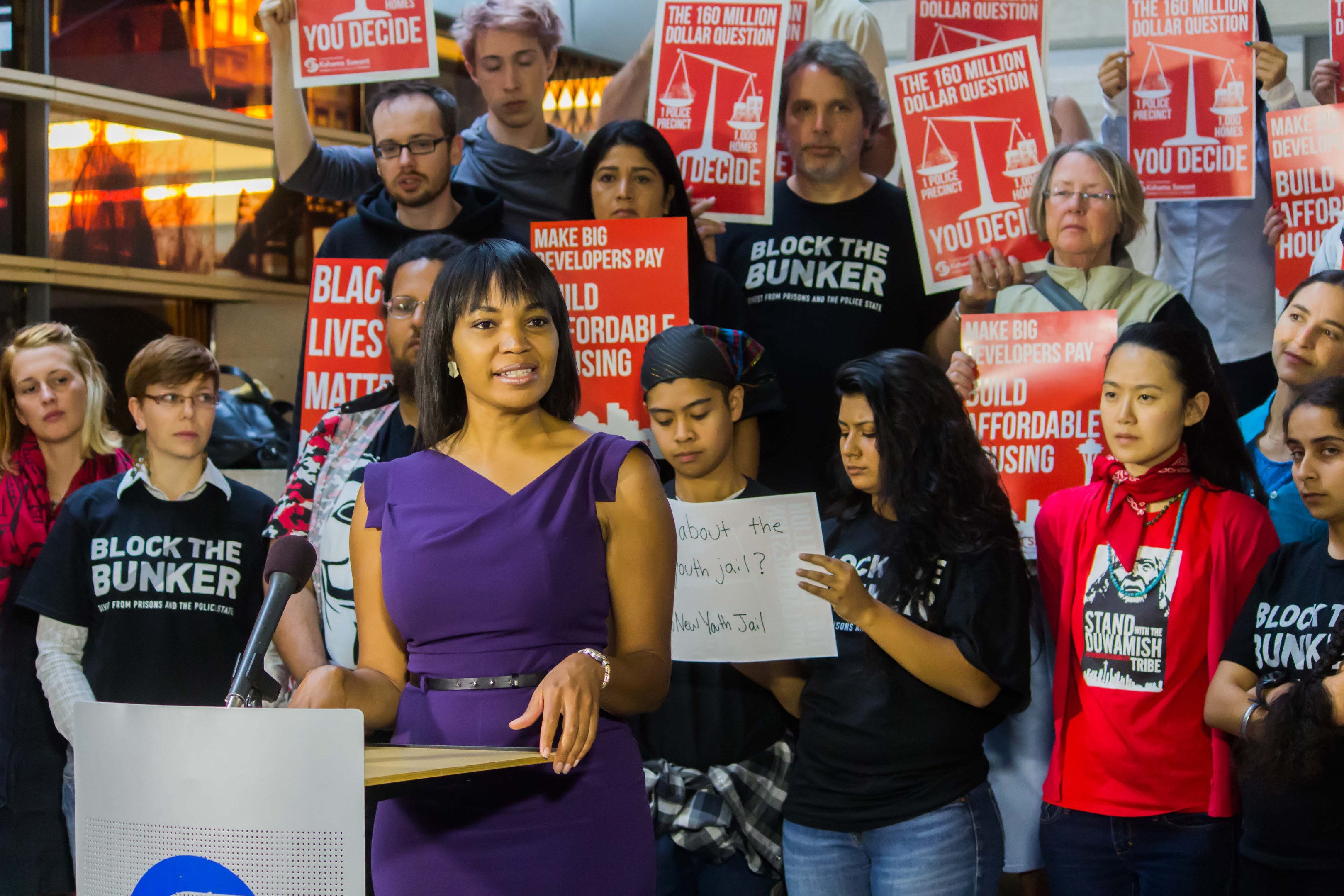 Eine Black-Lives-Matter-Aktivistin spricht vor einer Menge mit Schildern und Mikrofon.