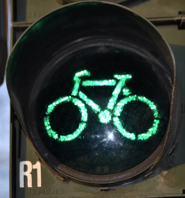 Grüne Ampel mit Fahrradsymbol, beleuchtet vor einer Wand.