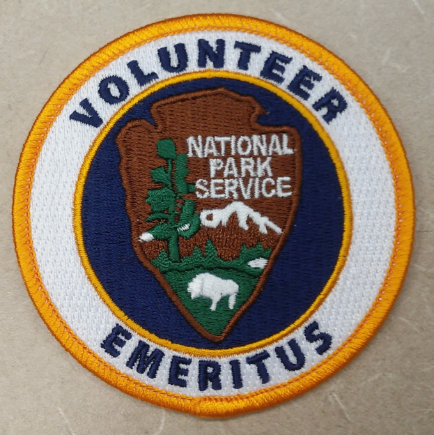 Runder Flicken mit blauem Rand und weißem Hintergrund, der den schwarzen Text 'Volunteer National Park Service Emeritus' in einem gelben Kreis zeigt.