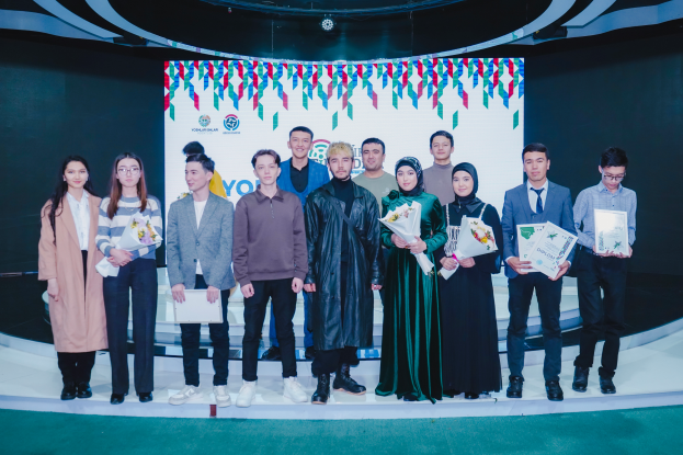 Eine Gruppe von Menschen auf einer Bühne, jeder hält einen Blumenstrauß und Urkunden in der Hand, im Hintergrund ein Schild mit der Aufschrift "Youth Solar Awards 2019."