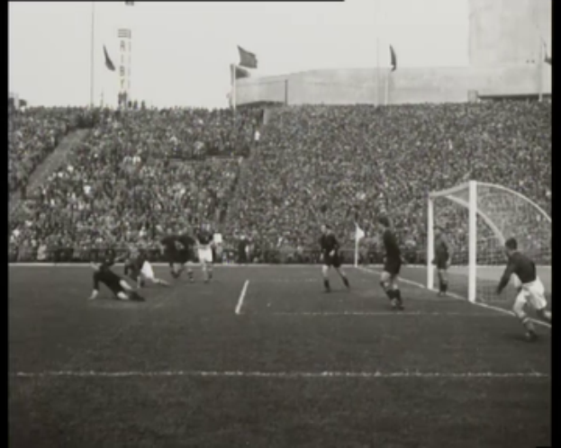 Ein Schwarz-Weiß-Foto eines Fußballspiels im Stadion, mit Spielern auf dem Feld und einem Torpfosten auf der rechten Seite, Zuschauern in den Rängen und Text oben und unten mit der Aufschrift "1958-1958 WM-Finale - Manchester United v Liverpool".