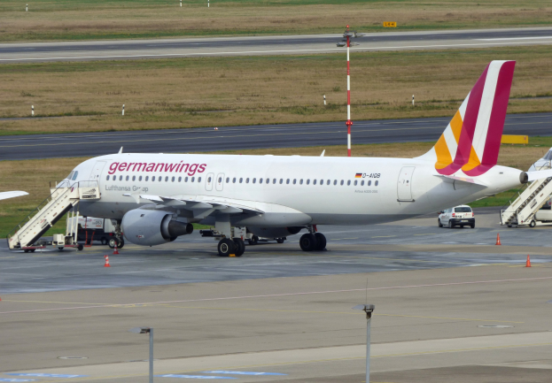 Germanwings Airbus A320-200 am Frankfurter Flughafen geparkt mit Servicefahrzeugen, Verkehrskegeln, Pfählen und Gras im Hintergrund.