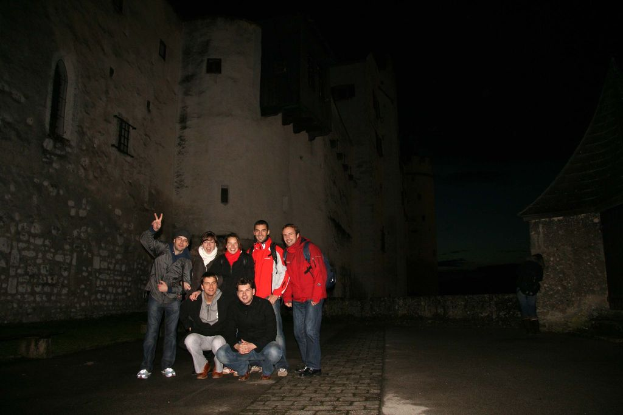 Menschen stehen in der Mitte einer nächtlichen Szene mit einem Schloss im Hintergrund.