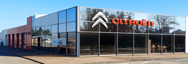 Ein Citroën-Händler mit Glaswänden und -türen, einer Straße davor und einem klaren blauen Himmel im Hintergrund.