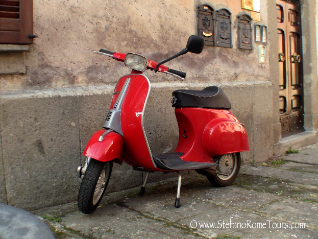 Ein roter Scooter steht vor einem Haus mit einer Tür und Fenstern auf einer Straße mit sichtbarem Text.