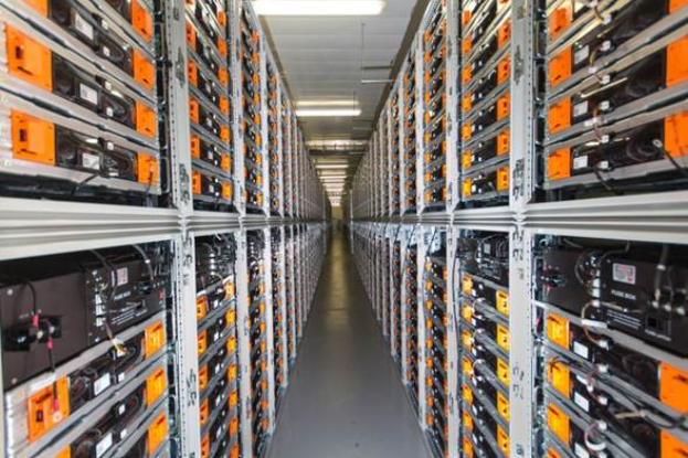 Eine lange Reihe von Servern in einem Rechenzentrum mit elektronischen Geräten in den Racks und Lampen oben.