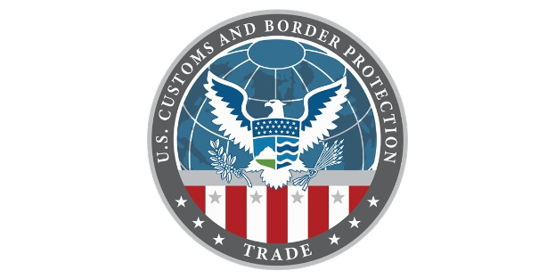 Logo der U.S. Zoll- und Grenzschutzbehörde Handel mit einem blauen Kreis mit einem weißen Stern, einer weißen Taube mit ausgebreiteten Flügeln und dem Text "U.S." über der Taube, alles auf einem weißen Rand.