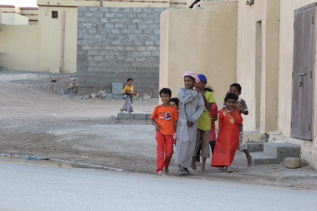 Eine Gruppe lÃ¤chelnder Kinder, die vor GebÃ¤uden, Wasser, Felsen und einer StraÃe stehen.