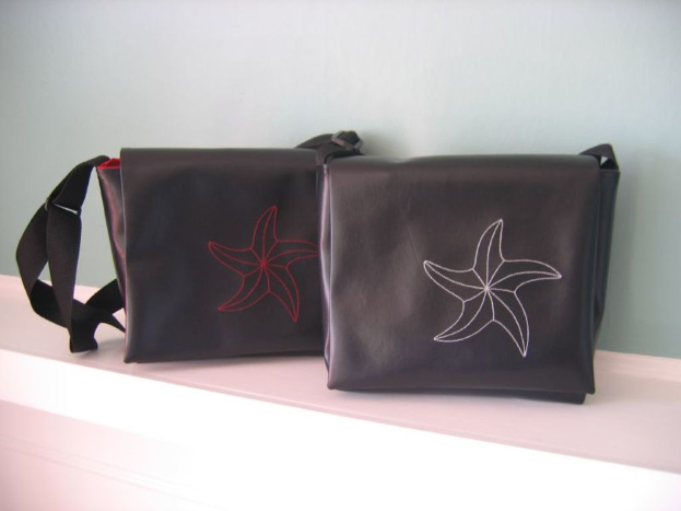 Zwei Handtaschen auf einem Regal, jede mit einem Blumenzeichen.