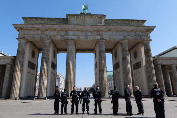 Gruppe von Polizisten vor dem Brandenburger Tor in Berlin, Deutschland, mit dem Torbogen, Säulen und Statue, umgeben von Gebäuden und einem sichtbaren Himmel.