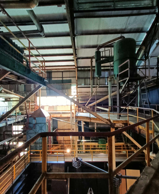 Ein großes industrielles Fabrikinnere mit verschiedenen Maschinen, einschließlich Geländern, Treppen, Pfählen und Geräten, das auf eine Pyrolyseanlage für Altreifen hinweist.