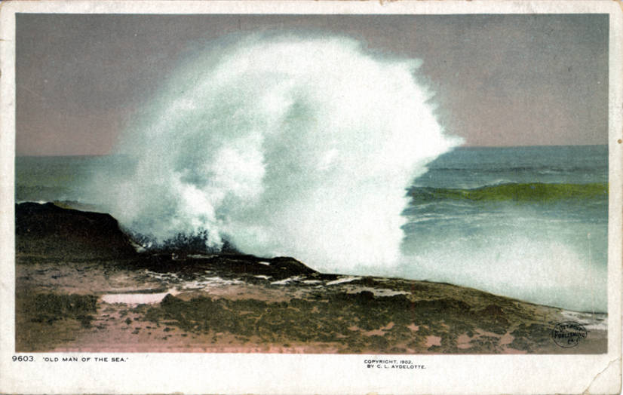 Ein altes Foto einer großen Welle, die auf einen Strand kracht, mit Wasser und Himmel im Hintergrund und Text unten.