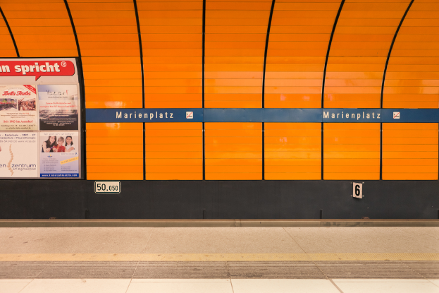 Ein Bahnsteig mit einer Werbetafel auf der linken Seite.