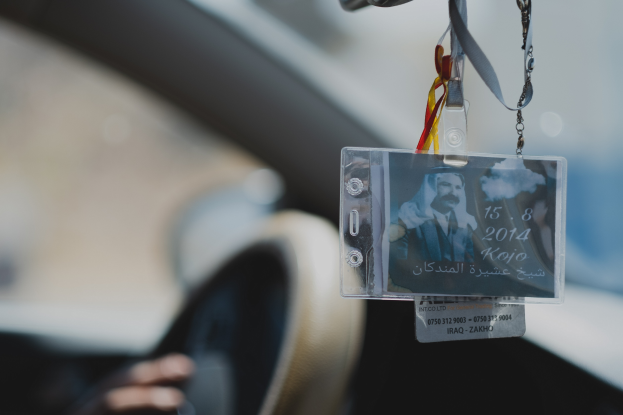 Eine Person fährt ein Auto mit einem ID-Karte am Lenkrad, ihre Hand ist auf der linken Seite zu sehen, mit einem unscharfen Hintergrund.
