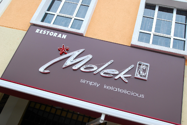 Ein Gebäude mit Fenstern und einer Werbetafel, auf der 'Molek' steht.