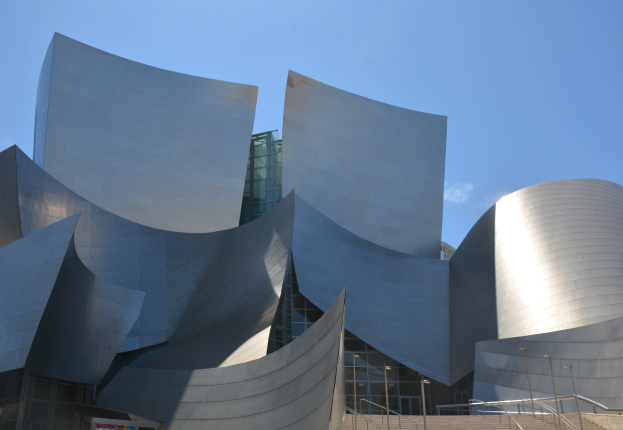 Das ARTIST Concert Hall in Los Angeles, ein modernes Gebäude mit Glaswänden, Treppen mit Geländern, die zum Eingang führen, umgeben von Laternenmasten, mit einer Tafel mit Text im Vordergrund und einem bewölkten Himmel im Hintergrund.