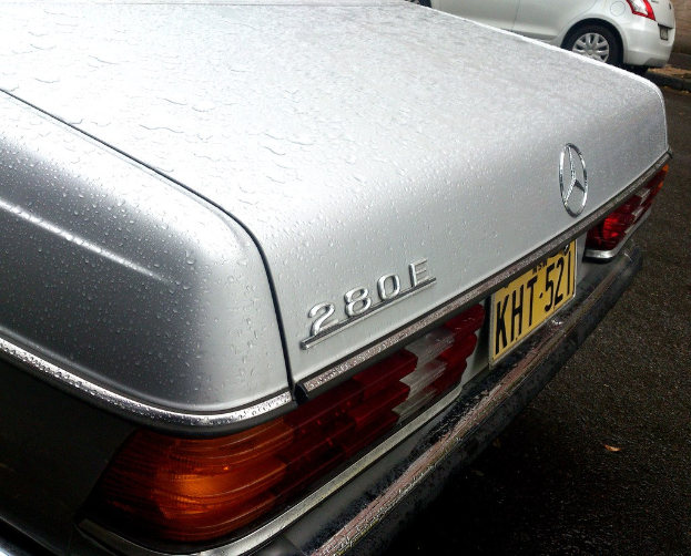 Mercedes-Benz-Logo auf einem Fahrzeug, das auf einer Straße mit einem anderen Fahrzeug neben ihm fährt.