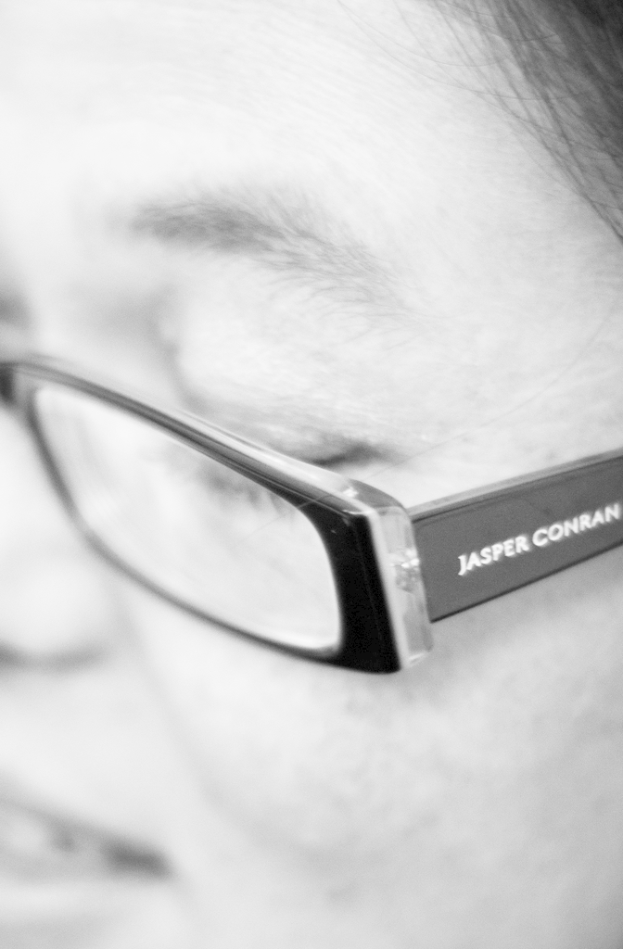 Ein Schwarz-Weiß-Mikrobild einer Person mit Brille und Text auf den Gläsern.