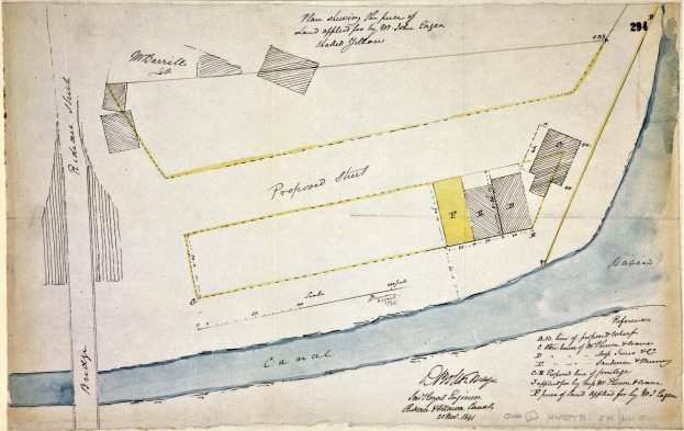 Ein detaillierter Plan eines vorgeschlagenen Standorts auf einem Blatt Papier, das Straßen, Gebäude und Landmarken zeigt, mit begleitendem Text, der die Größe, den Standort und die Merkmale des Standorts beschreibt.