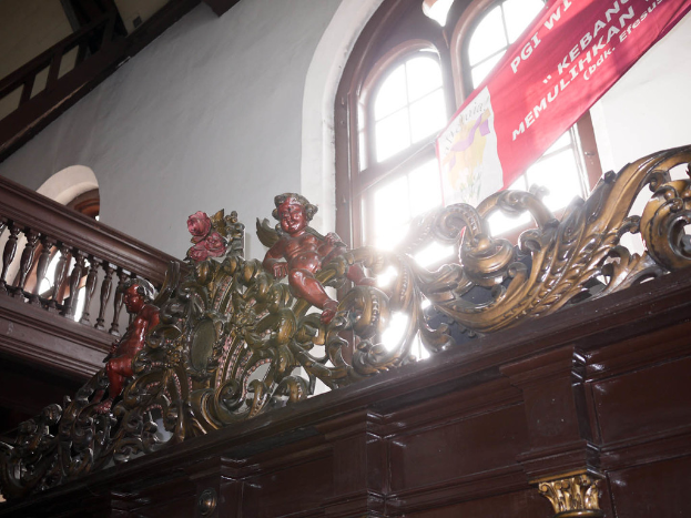 Schränke mit Statuen oben drauf, ein Fenster, Treppe und ein Banner darüber.