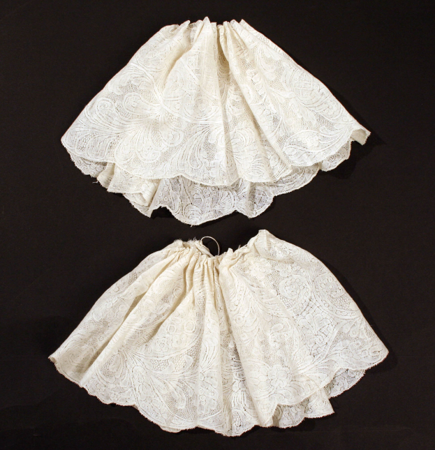 Zwei weiße Spitze-Röcke mit feinen Mustern auf schwarzem Hintergrund.