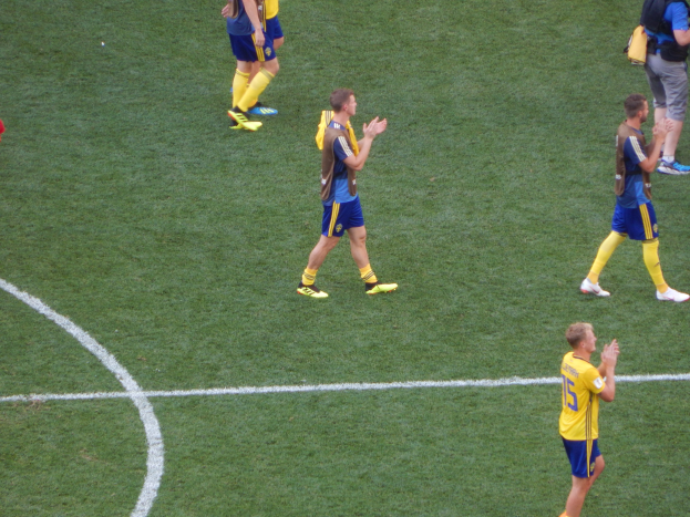 Mannengruppe in Fußballtrikots klatscht auf einem Fußballfeld.