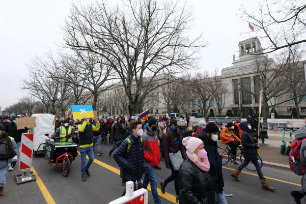 Eine große Gruppe von Menschen marschiert auf einer Straße in Washington, D.C., mit Schildern und Fahrrädern, mit Bäumen und einem Gebäude im Hintergrund bei klarem blauem Himmel am 21. Januar 2020.