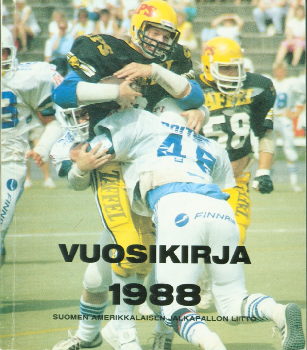 Eine Gruppe von Menschen in Sportbekleidung und Helmen, die Fußball auf einem Feld spielen, mit einigen Personen, die im Hintergrund auf einer Treppe sitzen; unten steht Text, der "Vuosikirja 1988 - Suomen Amerikkaisen Jalkapallon Litto" liest.