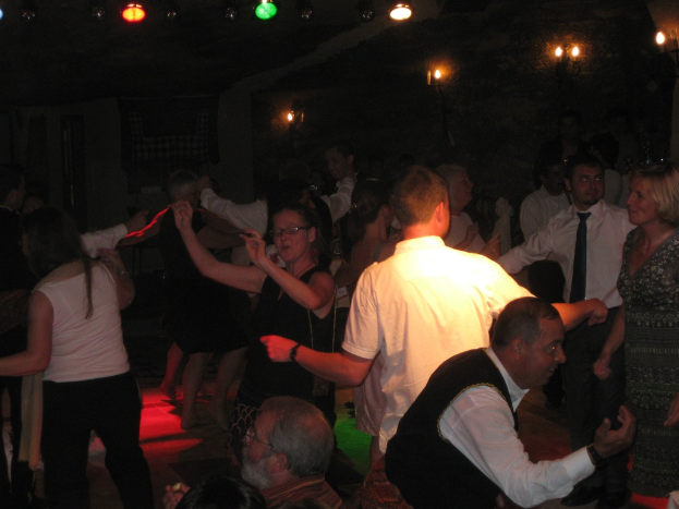 Lebendige Partyszene mit tanzenden Menschen unter einer Decke, die mit verschiedenen bunten Lichtern geschmückt ist.