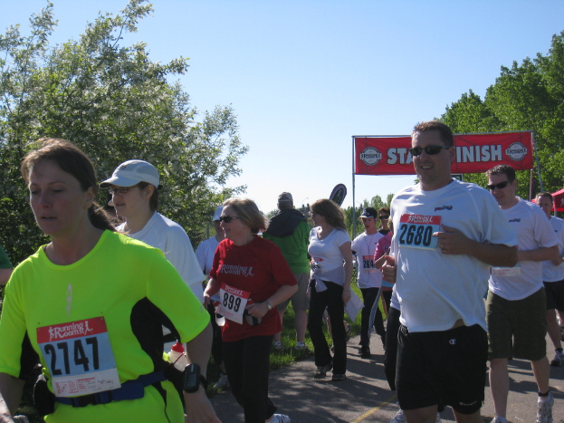 Eine Gruppe von Kindern, die bei einem Marathonlauf laufen, mit einem roten Banner und Bäumen im Hintergrund.