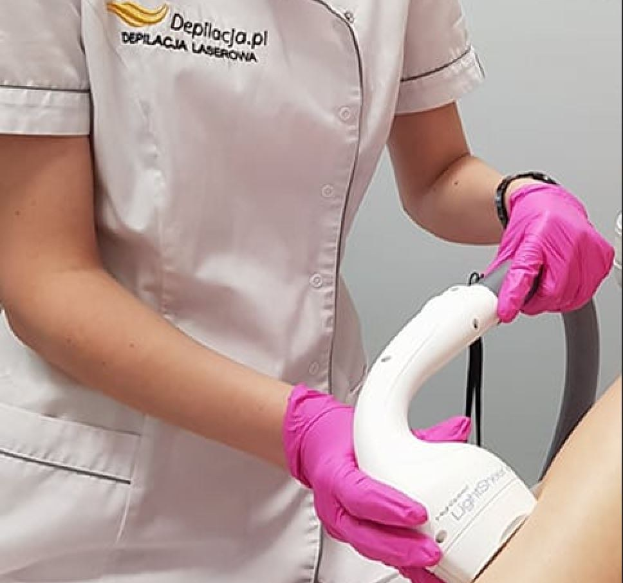 Eine Frau in einem weißen Hemd und pinken Handschuhen bedient eine weiße Laser-Haarfentfernungsmaschine an einer Wand.