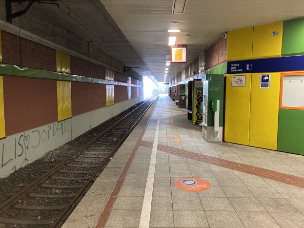 Ein Bahnsteig in Berlin Hauptbahnhof mit einem Zug auf den Schienen, beleuchtet von Deckenlampen, mit Graffiti an der linken Wand und ein paar Gegenständen auf der rechten Seite.
