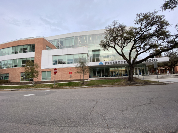 Großes zweistöckiges Backsteingebäude mit der Aufschrift "Presbyte Middle School" und vielen rechteckigen Fenstern, umgeben von Gras, Bäumen, Straßenschildern, Strommasten und einer asphaltierten Straße unter einem bewölkten Himmel.