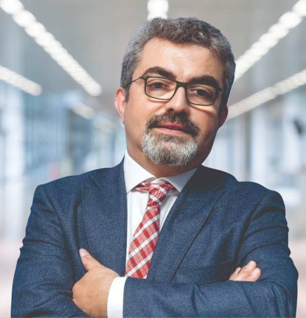 Ein Mann in Anzug und Krawatte mit verschränkten Armen, der eine Brille trägt und vor einem unscharfen Hintergrund steht, mit Text, der ihn als den neu ernannten Marketingchef identifiziert.