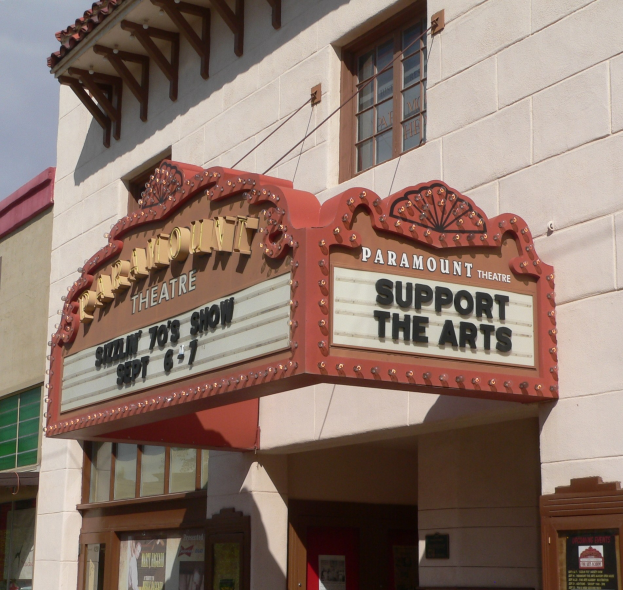 Außensicht des Paramount Theatre in Sacramento, Kalifornien, mit Glasfenstern und -türen, einem "Support the Arts"-Schild und einem sichtbaren Himmel im Hintergrund.